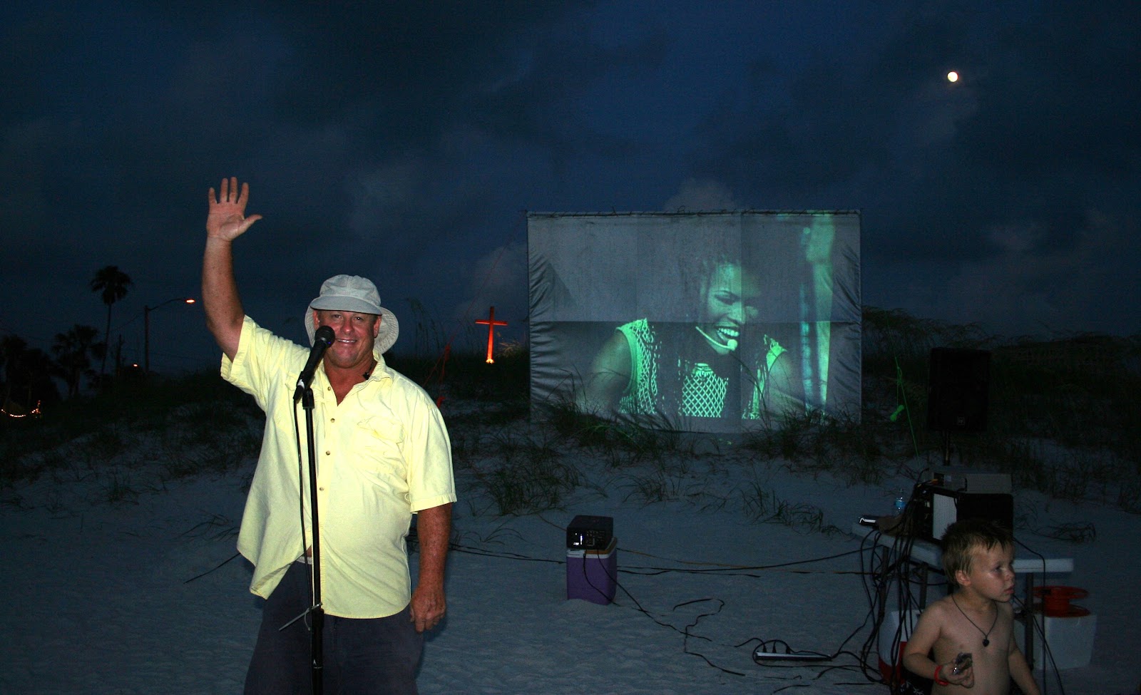 Pastor Tommy waving to families at a Reach and Teach movie night on the beach